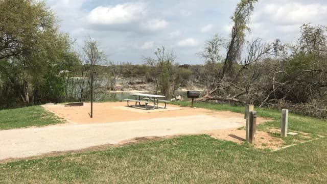 Picnic table, grill, and fire ring with Waco Lake in the background