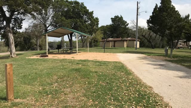 RV site with grill, fire ring, covered picnic table, and restroom/shower facilities nearby