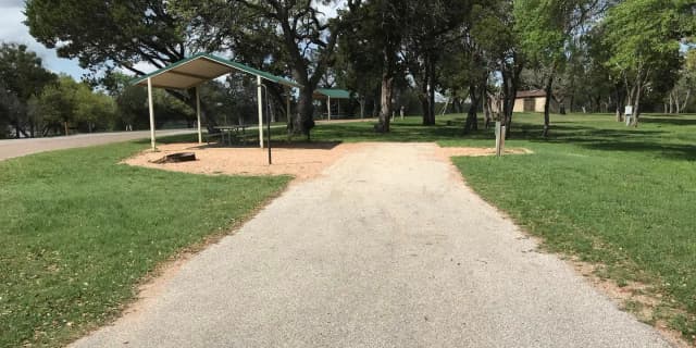 RV site with grill, fire ring, covered picnic table, and restroom/shower facilities nearby