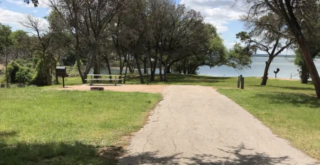 RV site with picnic table, grill, fire ring, and Waco Lake in the background