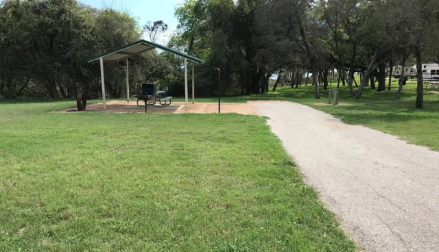 RV site with covered picnic table, grill, and fire ring