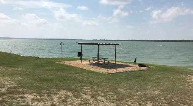 Tent site with picnic table, grill, and fire ring.  Site is located very close to shoreline of Waco Lake
