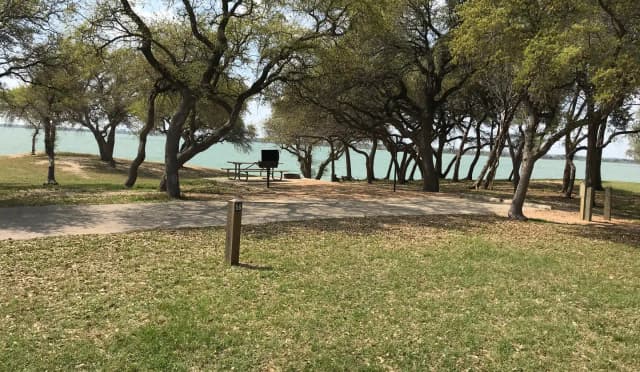 RV site with picnic table, grill, fire ring, and Waco Lake in the background