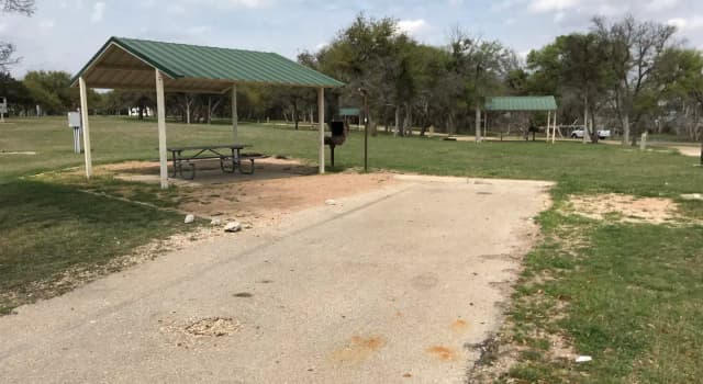 RV site with covered picnic table, grill, and fire ring