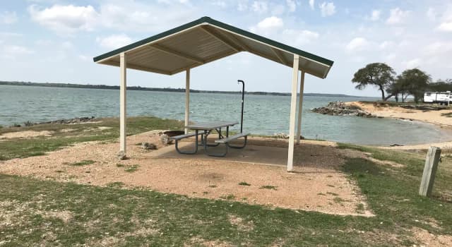 Tent site with covered picnic table and fire ring.  Site is located very close to shoreline of Waco Lake