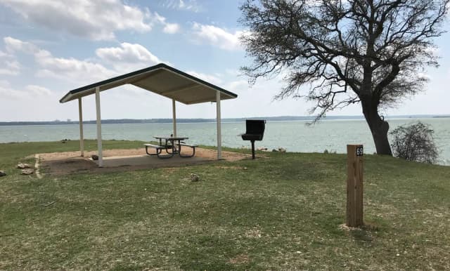 Tent site with covered picnic table, grill, and fire ring.  Site is located very close to shoreline of Waco Lake