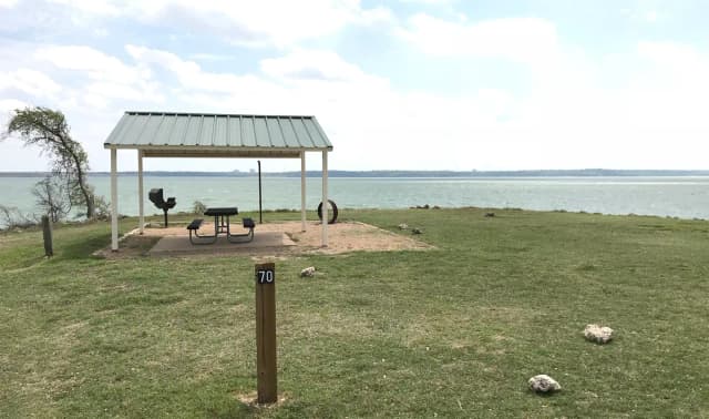 Tent site with covered picnic table, grill, and fire ring.  Site is located very close to shoreline of Waco Lake