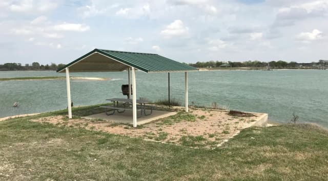 Tent site with covered picnic table, grill, and fire ring.  Site is located very close to shoreline of Waco Lake