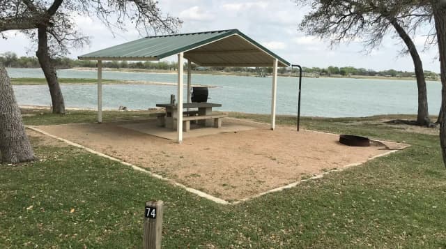 Tent site with covered picnic table, grill, and fire ring.  Site is located very close to shoreline of Waco Lake