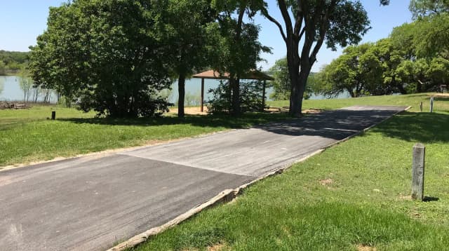 RV site with covered picnic table, grill, fire ring, and Waco Lake in the background