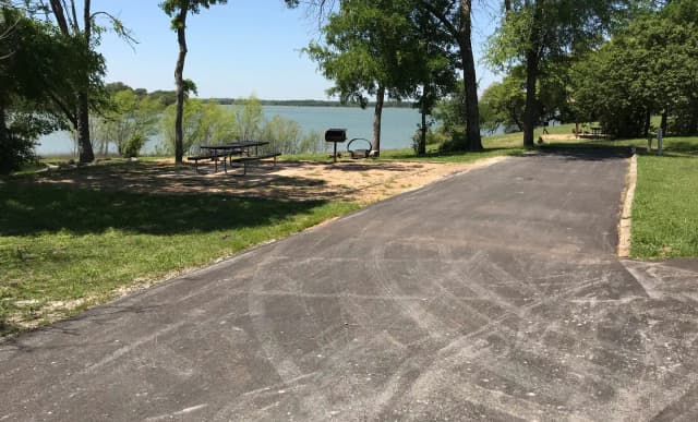 RV site with picnic table, grill, fire ring, and Waco Lake in the background Ca