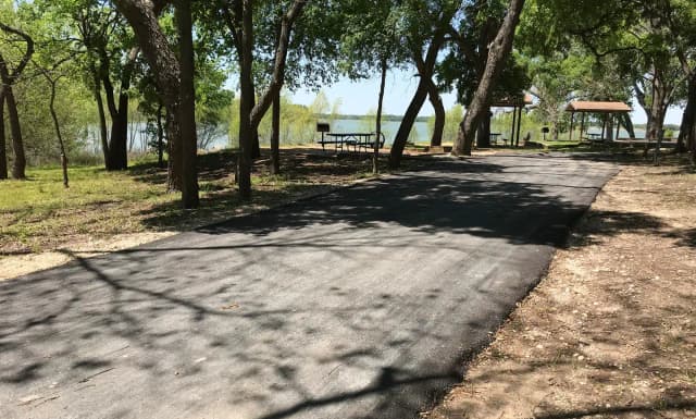 RV site with picnic table, grill, fire ring, and Waco Lake in the background