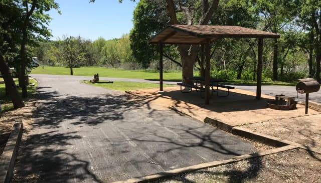 RV site with covered picnic table, grill, and fire ring