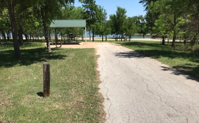 RV site with covered picnic table, grill, fire ring, and Waco Lake in the background