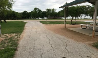 Covered picnic table, grill, and fire ring with Waco Lake in the background
