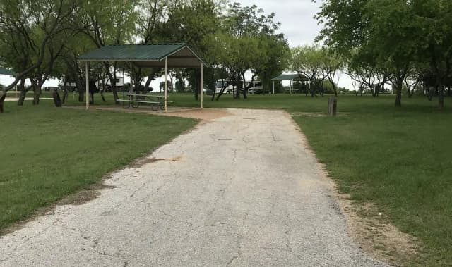 RV site with covered picnic table, grill, and fire ring