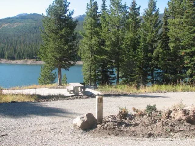 Site 11, campsite surrounded by pine trees, picnic table & fire ring
