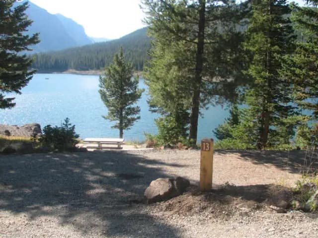 Site 13, campsite surrounded by pine trees, picnic table & fire ring