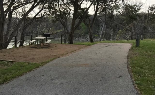 RV site with picnic table, grill, and Waco Lake in the background