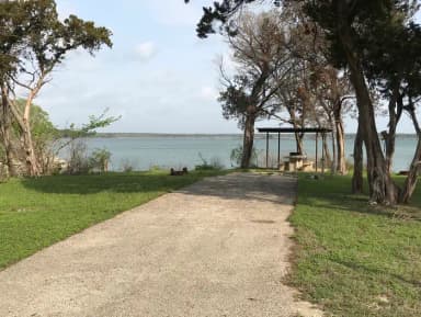 RV site with covered picnic table, grill, fire ring, and Waco Lake in the background