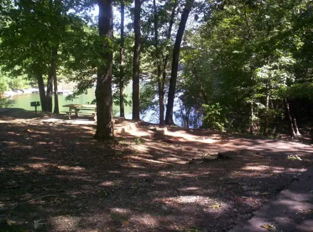 Path way down to wide dirt site, picnic table.
