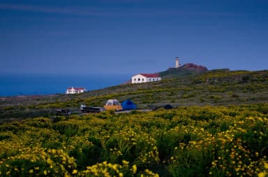 Two tents on terrace overlooking ocean, two buildings, and lighthouse., filed by the agency against 7 campsites at Anacapa Island