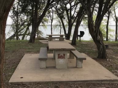 Picnic table, grill, and fire ring at site with Waco Lake in the background