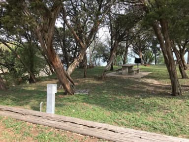 Picnic table and grill at site with Waco Lake in the background
