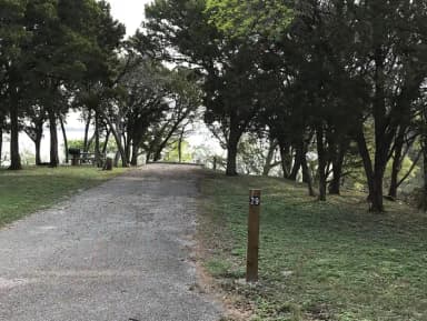 RV site with picnic table, grill, fire ring, and Waco Lake in the background