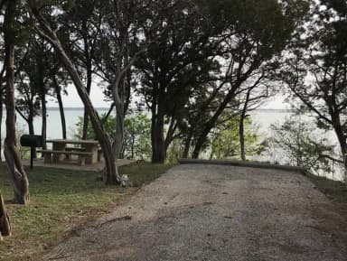 RV site with picnic table, grill, fire ring, and Waco Lake in the background