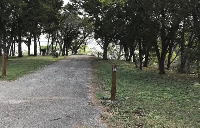 RV site with picnic table, grill, fire ring, and Waco Lake in the background
