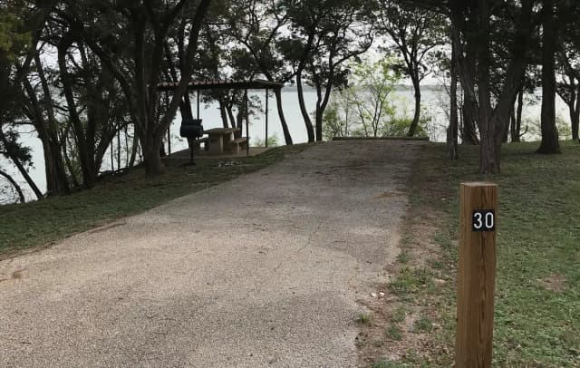 RV site with covered picnic table, grill, and Waco Lake in the background