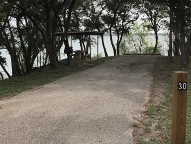 RV site with covered picnic table, grill, and Waco Lake in the background