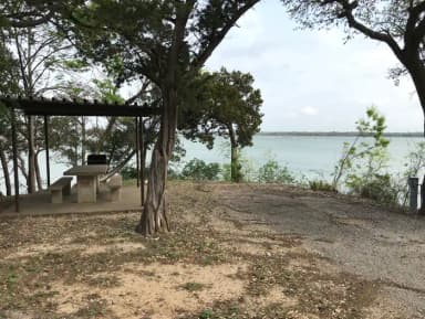 RV site with covered picnic table, grill, and Waco Lake in the background