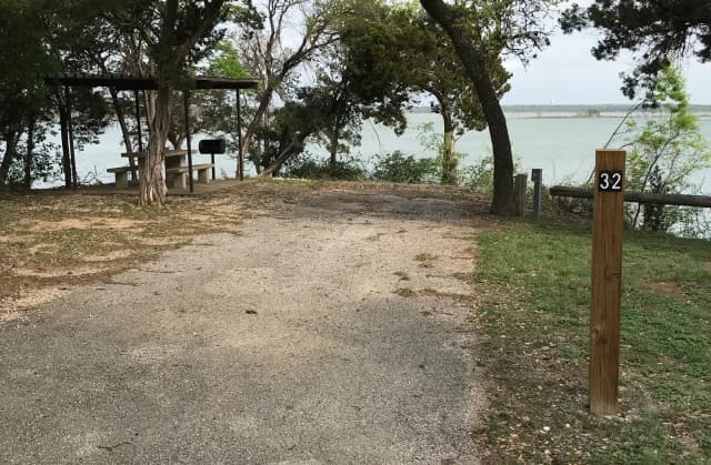RV site with covered picnic table, grill, and Waco Lake in the background