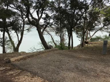 RV site with covered picnic table, grill, and Waco Lake in the background