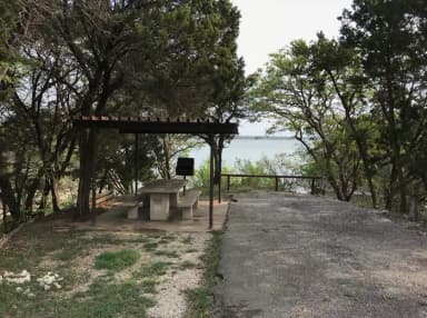 RV site with covered picnic table, grill, and Waco Lake in the background
