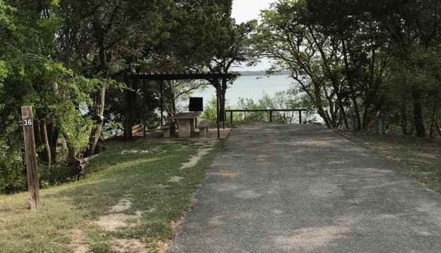 RV site with covered picnic table, grill, and Waco Lake in the background