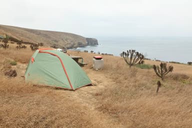 Tent sitting in dried grass on a ocean bluff overlooking the coastline., filed by the agency against 10 campsites at Santa Barbara Island