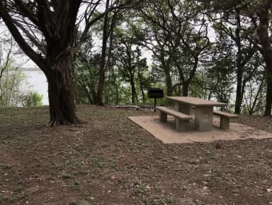 Tent site with picnic table, grill, and Waco Lake in the background