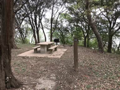 Tent site with picnic table, grill, and Waco Lake in the background