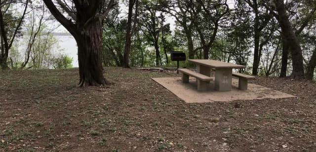 Tent site with picnic table, grill, and Waco Lake in the background