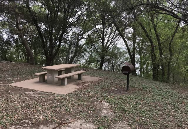 Tent site with picnic table, grill, and Waco Lake in the background