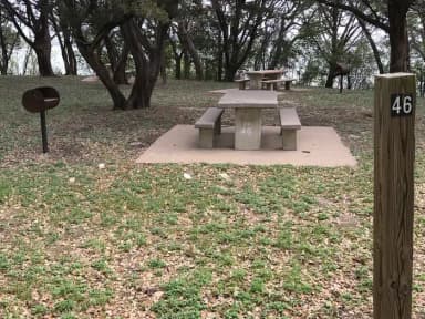 Tent site with picnic table, grill, and Waco Lake in the background