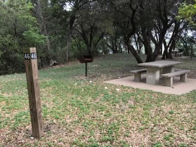 Tent site with picnic table, grill, and Waco Lake in the background