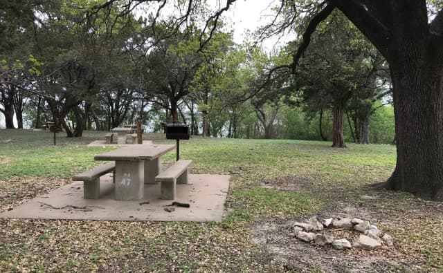 Tent site with picnic table, grill, and Waco Lake in the background