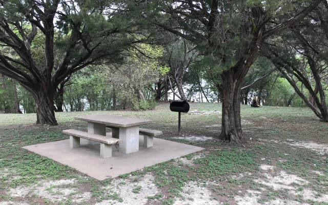 Tent site with picnic table, grill, and Waco Lake in the background