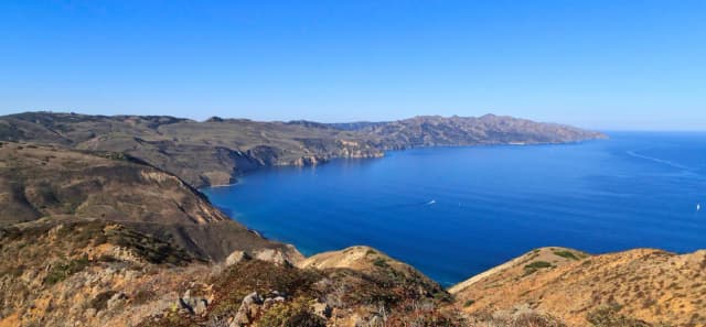 View from a high ridge overlooking the rest of a long, narrow, rugged island with steep cliffs.