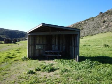 Eight foot tall wind shelter with picnic table surrounded by green grass.