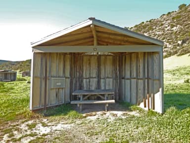 Eight foot tall wind shelter with picnic table surrounded by green grass.